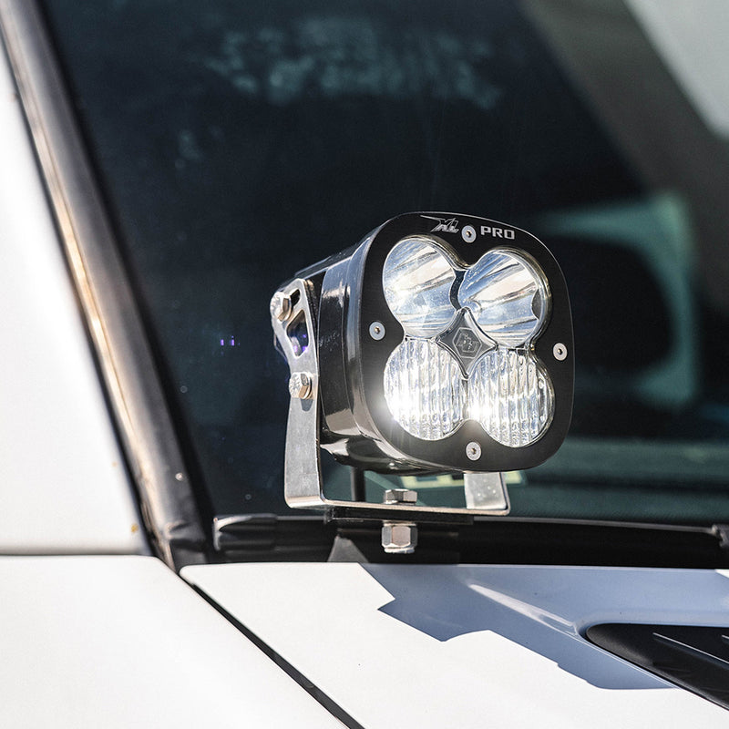 Baja Designs Van XL Pro A-Pillar Kit on a Mercedes-Benz Sprinter: A lit XL Pro LED pod mounted on an A-pillar bracket at the base of a white van windshield