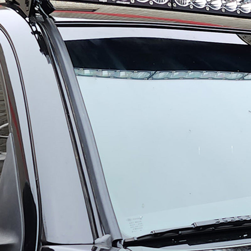 Baja Designs Wire Hider Kits on a vehicle: A black wire hider runs along the A-pillar of a dark vehicle beneath a roof-mounted LED light bar