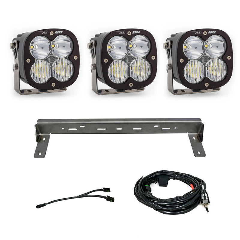 Baja Designs XL 80 Bumper Kit, complete kit on a studio background: three XL80 LED pods with clear lenses, a steel bumper mounting bar and wiring harnesses on a white background