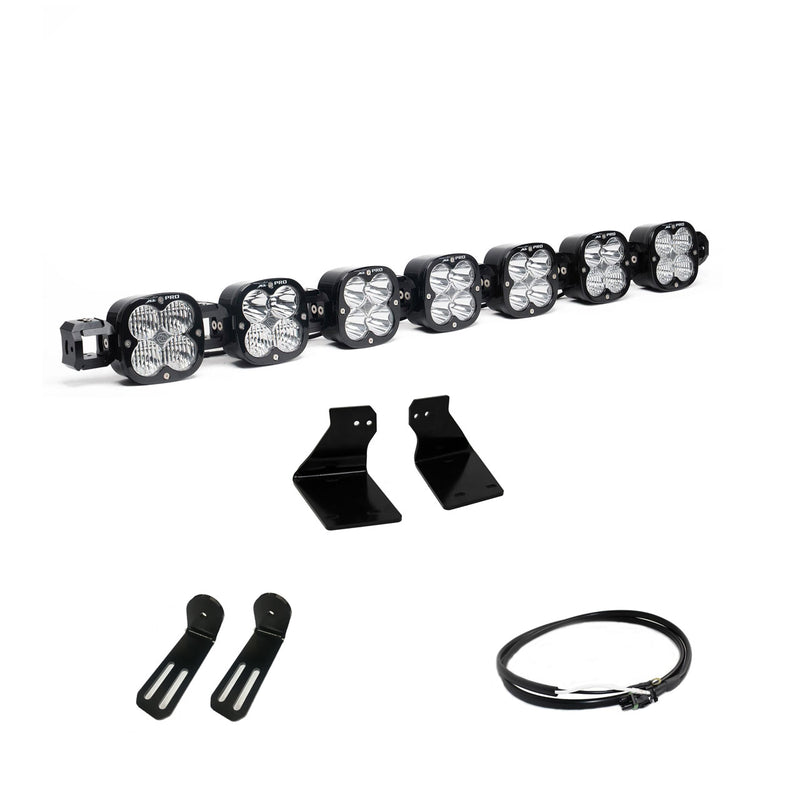 Baja Designs XL Linkable Bumper Light Kit, complete kit on a studio background: A seven-pod XL Linkable light bar kit on white with two bumper brackets, two slotted mounts and a short coiled pigtail harness