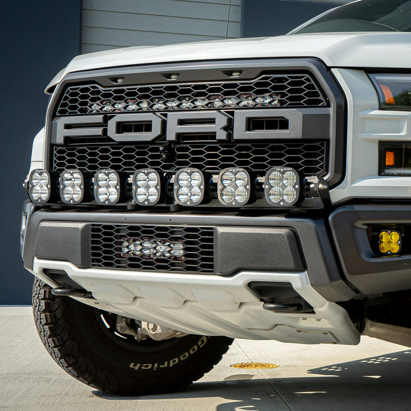 Baja Designs XL Linkable Bumper Light Kit on a Ford F-150 Raptor: A white Ford F-150 Raptor front with a seven-pod XL Linkable light bar below the FORD grille