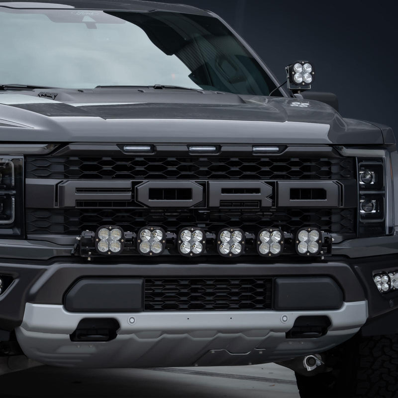 Baja Designs XL Linkable Bumper Light Kit on a Ford F-150 Raptor: close front view of a gray late-model Ford Raptor with six XL pods below the FORD grille lettering and a pod on the A-pillar
