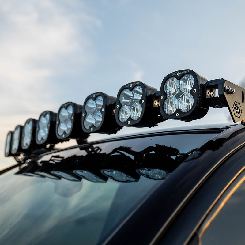 Baja Designs XL Linkable Light Bar Roof Kit on a vehicle: square LED pods on a linkable bar sit across the roof of a dark vehicle under a cloudy sky