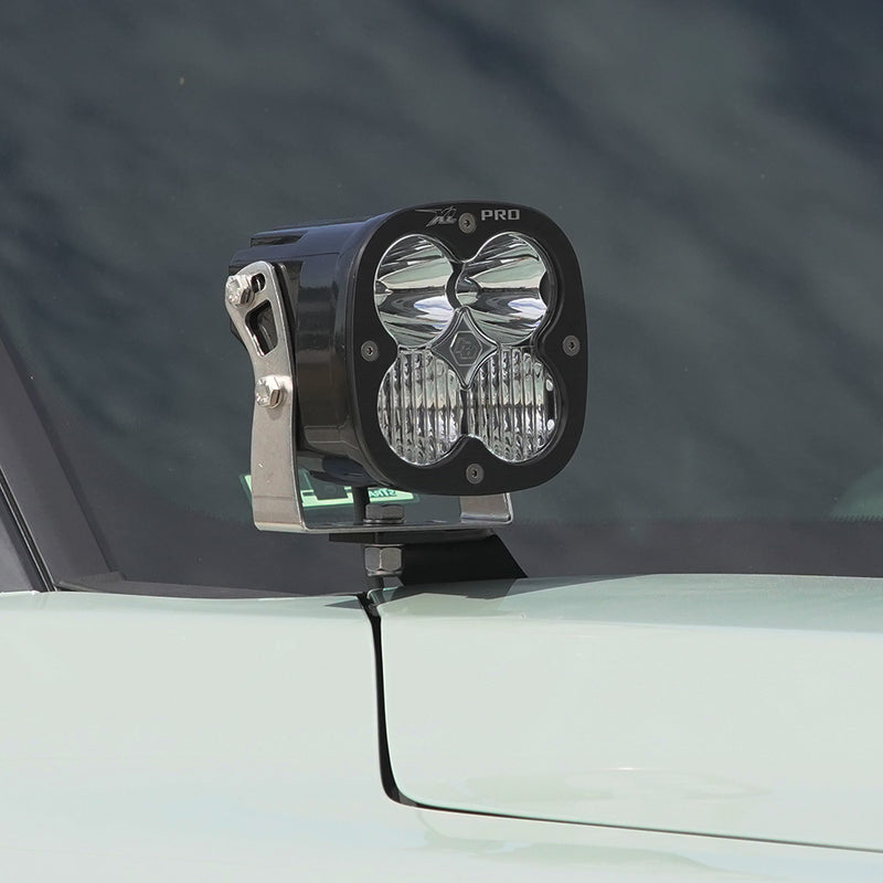Baja Designs XL Pro A-Pillar Light Kit on a vehicle: A Baja Designs XL Pro LED pod mounted on an A-pillar bracket beside the windshield of a pale green truck