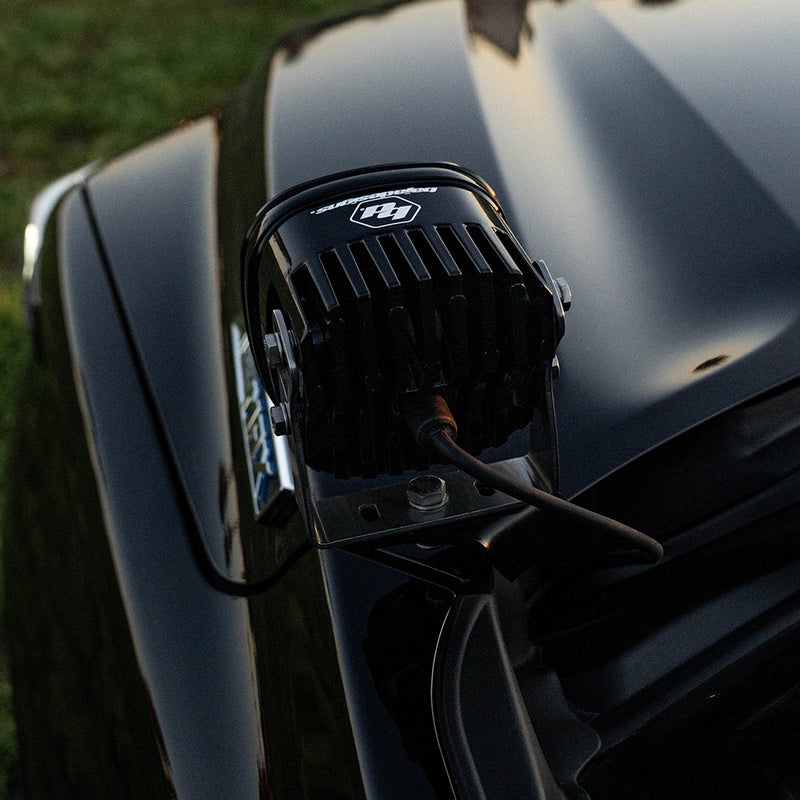 Baja Designs XL Pro A-Pillar Light Kit on a vehicle: the back of a Baja Designs XL LED pod mounted on the A-pillar of a black truck in low evening light