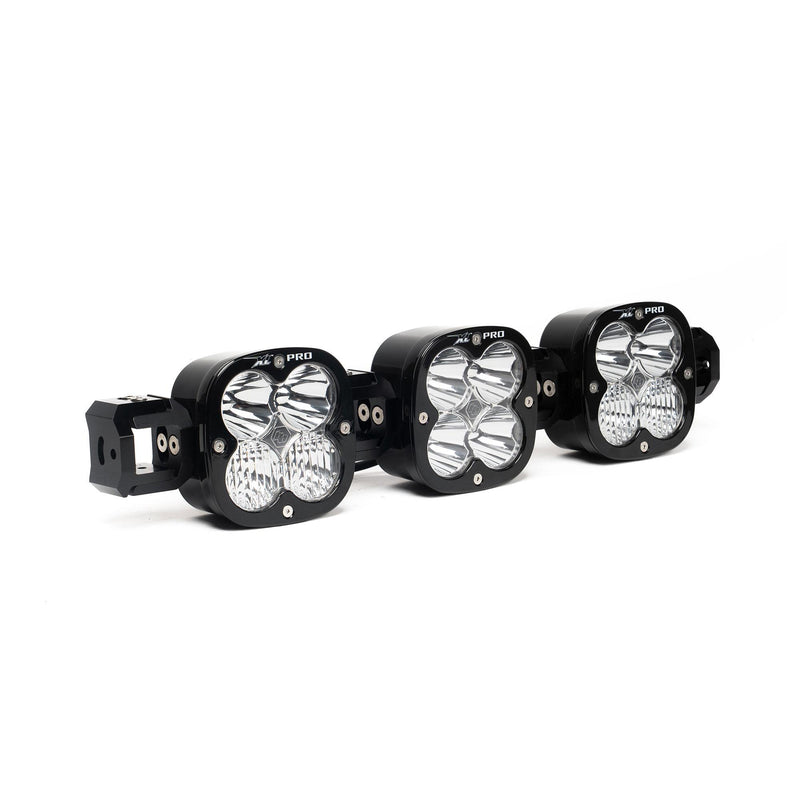 Baja Designs XL Pro Linkable LED Light Bar, whole product on a studio background: A 3-light black XL Pro Linkable LED light bar with clear lenses and end mounting blocks, shown at a close front three-quarter angle on a white background
