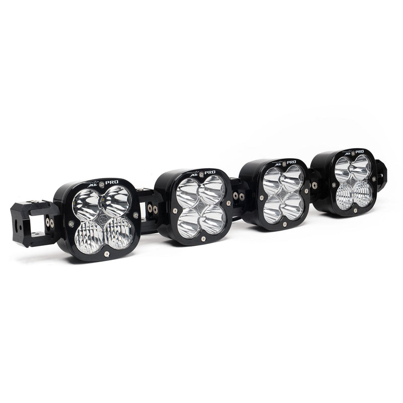 Baja Designs XL Pro Linkable LED Light Bar, whole product on a studio background: A 4-light black XL Pro Linkable LED light bar with clear lenses and end mounting blocks, shown at a front three-quarter angle on a white background