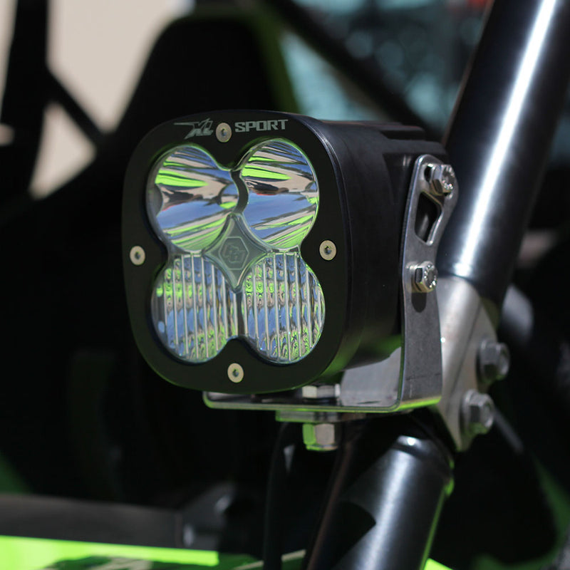 Baja Designs XL Sport LED Auxiliary Light Pod Pair on a UTV (make not identifiable): A black Baja Designs XL Sport LED pod with a clear lens clamped to the roll cage tube of a green side-by-side