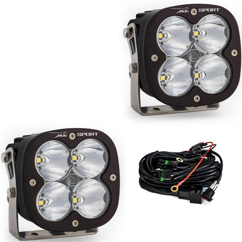 Baja Designs XL Sport LED Auxiliary Light Pod Pair, whole product on a studio background: A pair of black square Baja Designs XL Sport LED light pods with clear spot lenses and a wiring harness, shown on white