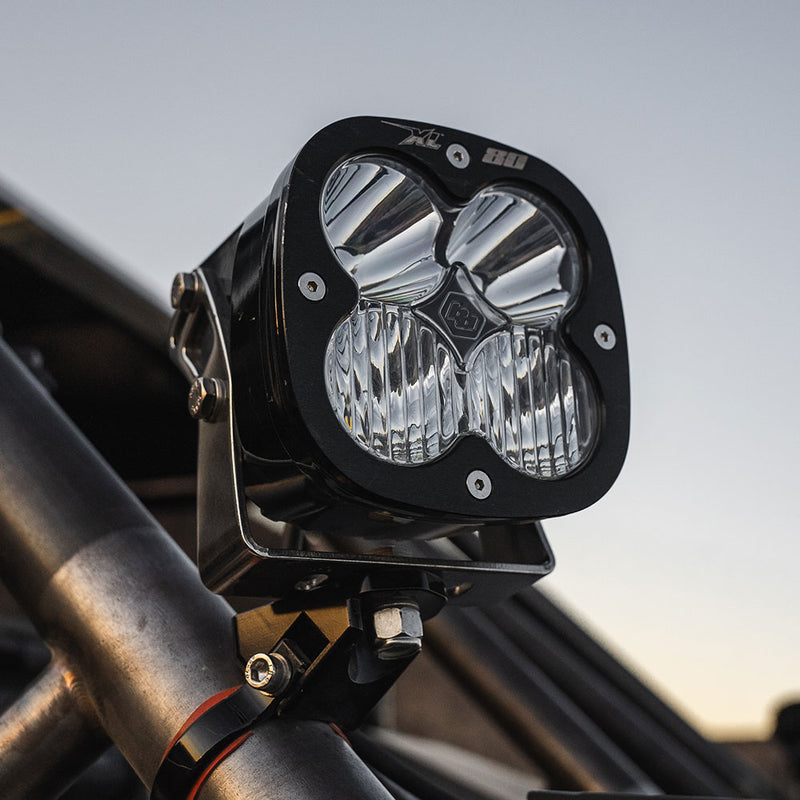 Baja Designs XL80 LED Auxiliary Light Pod on a UTV (make not identifiable): A black Baja Designs XL80 LED pod with a clear lens clamped to a roll cage tube against an evening sky