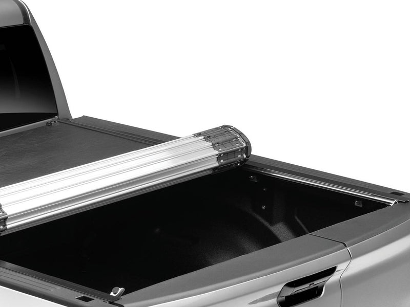 BAK Revolver X2 hard roll-up tonneau cover partly rolled toward the cab, silver slat canister above the open bed