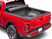 BAK Revolver X4s tonneau cover fully rolled up into its canister at the cab of a red Ford F-150 Lightning, exposing the empty carpeted truck bed