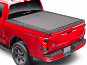 BAK Revolver X4s hard roll-up tonneau cover in matte black closed over the bed of a red Ford F-150 Lightning, shown from the rear three-quarter angle