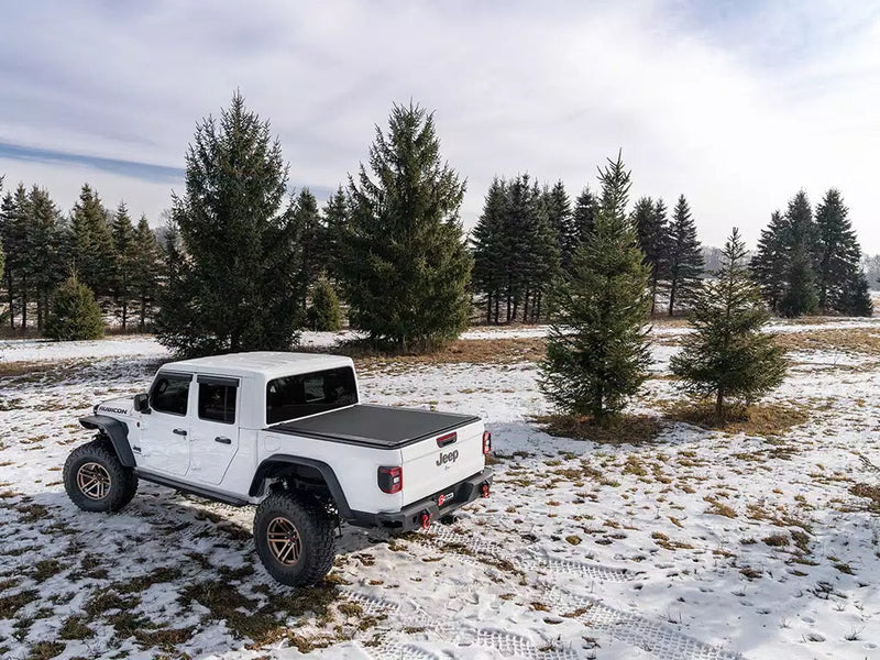 White pickup with the Revolver X4s cover closed, parked in a snowy field