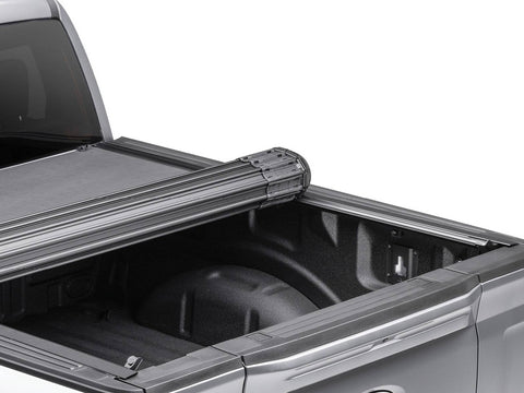 BAK Revolver X4s hard roll-up tonneau cover partly rolled toward the cab, black slat canister above the open bed