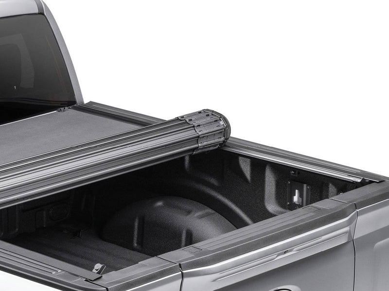 BAK Revolver X4s hard roll-up tonneau cover partly rolled toward the cab, black slat canister above the open bed