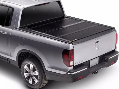 BAKFlip F1 hard folding tonneau cover in matte black closed over the bed of a silver Honda Ridgeline, shown from the rear three-quarter angle