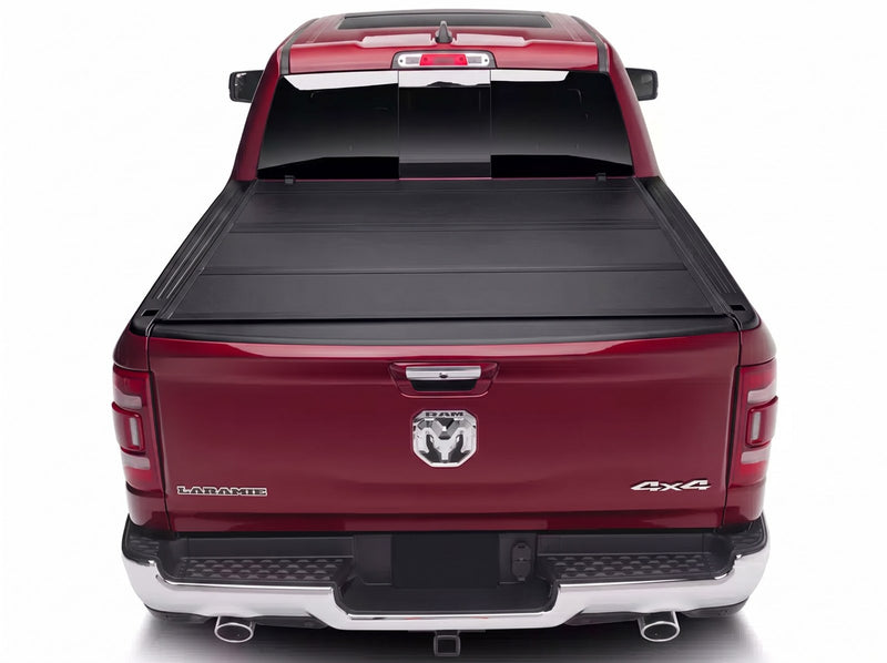 BAK BAKFlip MX4 tonneau cover closed flush across the bed of a dark red Ram 1500 Laramie viewed straight on from behind the tailgate