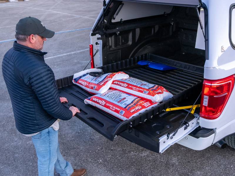 Man rolling the BEDSLIDE 500Go tray out of the truck bed to reach bagged cargo