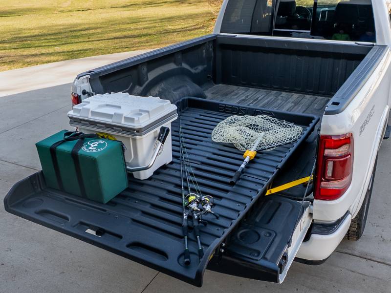 BEDSLIDE 500Go rolling cargo tray pulled out of a full-size pickup bed, loaded with a cooler and fishing gear