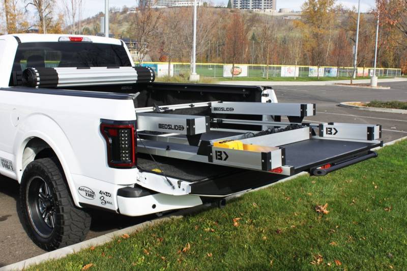 Silver BEDSLIDE extended out of a white pickup with the BEDBIN kit fitted, photographed outdoors