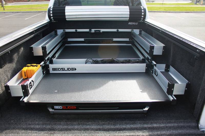 Silver BEDSLIDE fitted with the complete BEDBIN kit inside a truck bed, deck extended with the side and mini bins in place