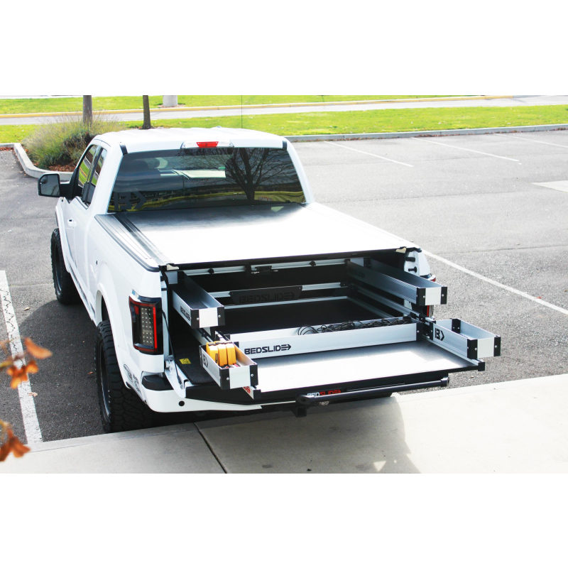 Wide view of a pickup with the BEDSLIDE deck rolled out and the silver BEDBIN kit fitted
