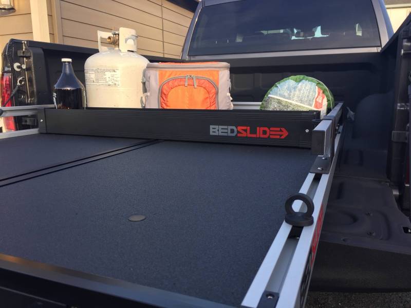 Black Edition BEDSLIDE BEDBIN deck divider on a slide deck holding a cooler and other gear against it
