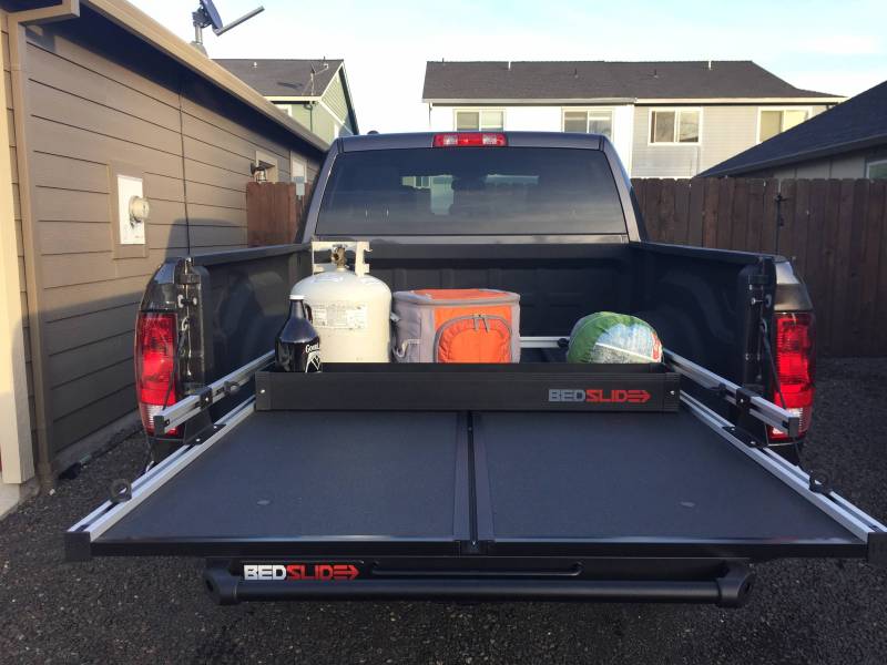 Wide view of a pickup with the BEDSLIDE deck rolled out and the black deck divider in place across it