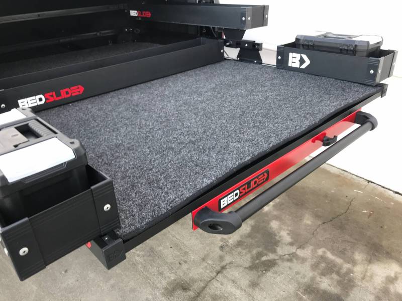 Black Mini Kix bin holding stacked tool cases beside a loaded BEDSLIDE deck