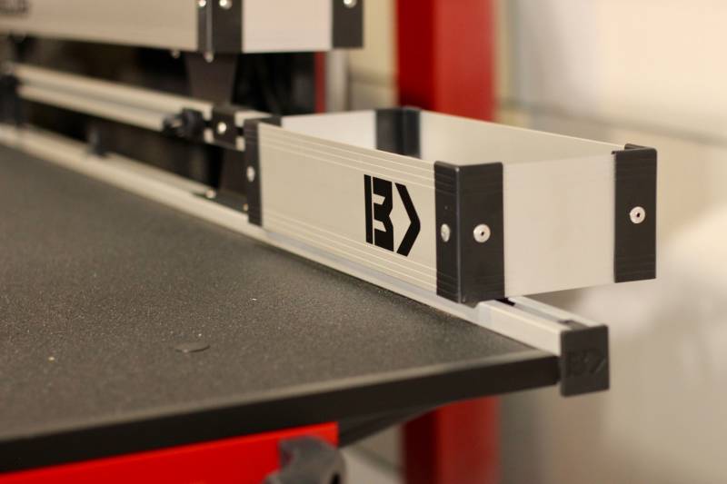 Silver Mini Kix bin mounted outboard on the BEDTRAX rail at the tailgate end of a BEDSLIDE deck