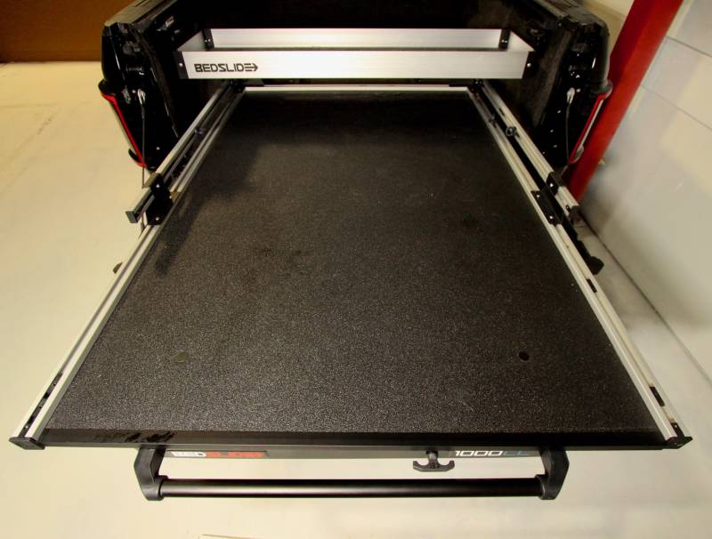 Silver upper BEDBIN tray installed above a BEDSLIDE deck inside a truck bed