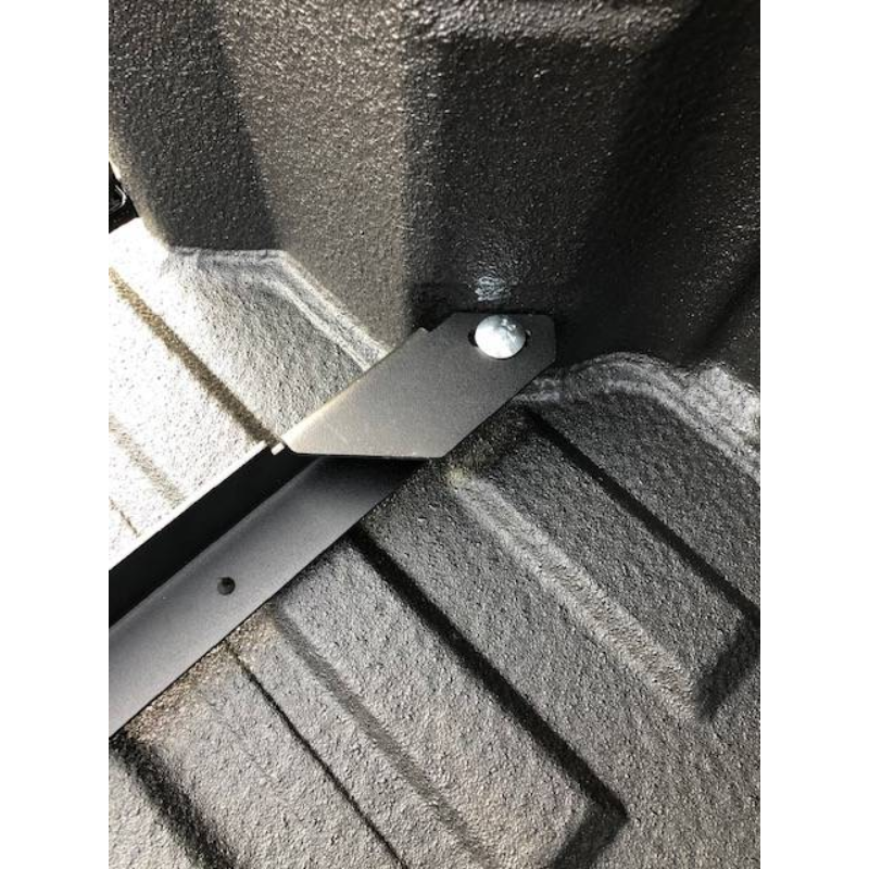 Close-up of a BEDSLIDE no-drill bracket arm running into the corner of a spray-lined truck bed and fastened at a single point