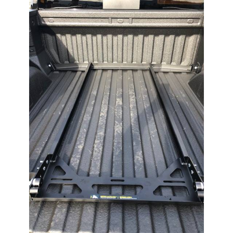 BEDSLIDE no-drill mounting brackets fitted across the floor of a full-size spray-lined truck bed, viewed from the tailgate before the slide goes on