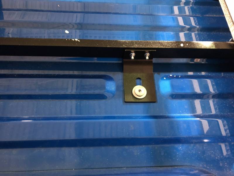 Second BEDSLIDE no-drill bracket location in a blue Ford truck bed with the crossbar running from it