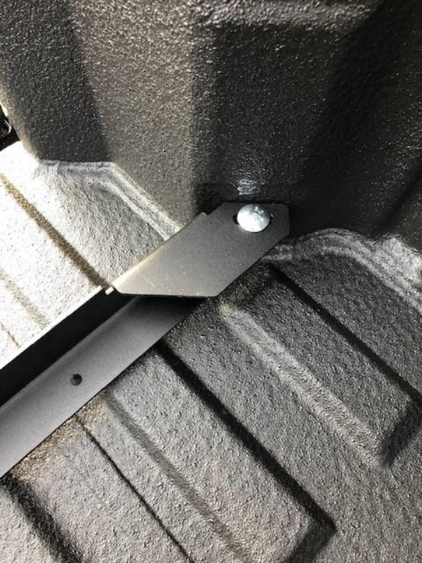 Close-up of a BEDSLIDE no-drill bracket fastened at a single point in the corner of a spray-lined truck bed