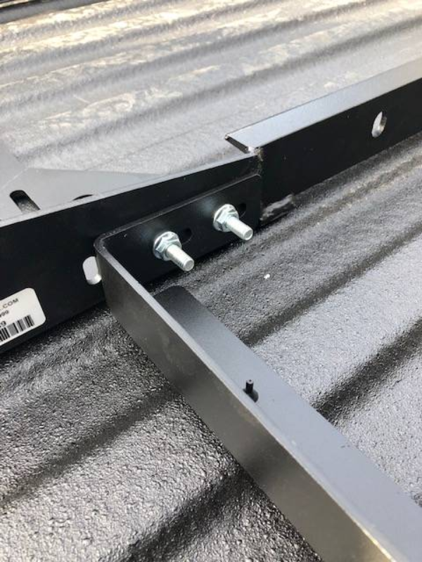 Close-up of the two mounting studs and the crossbar joint on a BEDSLIDE no-drill bracket inside a truck bed