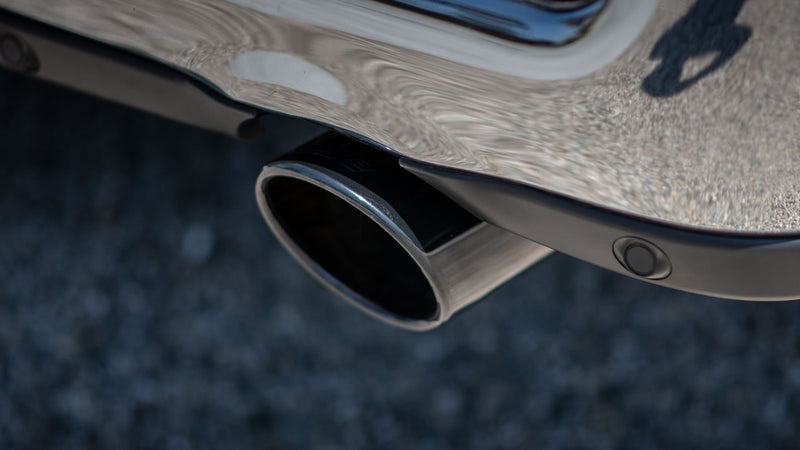 Borla ATAK Cat-Back Exhaust System on a vehicle: A close-up of a single Borla exhaust tip exiting beneath a chrome rear bumper
