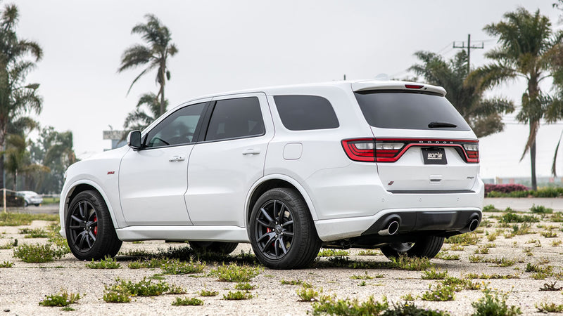 Borla ATAK Cat-Back Exhaust System installed on a Dodge Durango SRT: A white Dodge Durango SRT parked on gravel by palm trees, seen from the rear quarter with dual exhaust tips