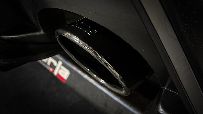 Borla ATAK Cat-Back Exhaust System on a vehicle: close-up of a dark chrome exhaust tip with a Borla logo under a dark rear bumper