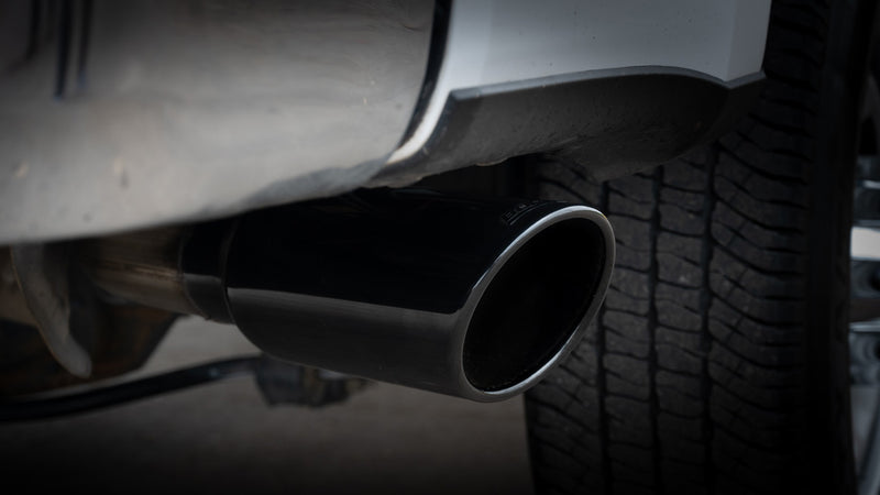 Borla ATAK Cat-Back Exhaust System on a vehicle: close view of a black chrome exhaust tip exiting ahead of a rear tire