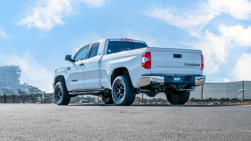 Borla ATAK Cat-Back Exhaust System installed on a Toyota Tundra: white Toyota Tundra double cab seen from the rear quarter under a blue sky with exhaust under the rear bumper