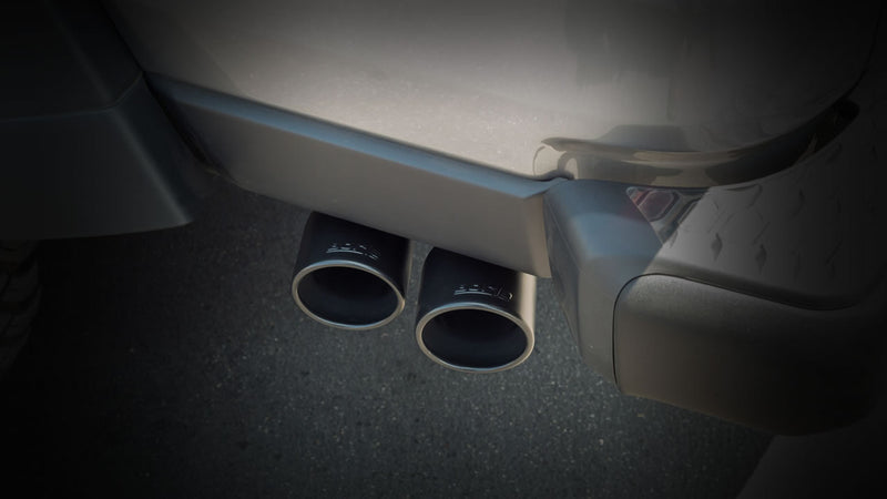 Borla Exhaust Tip Kit: dark close view of two black Borla exhaust tips installed under a rear bumper
