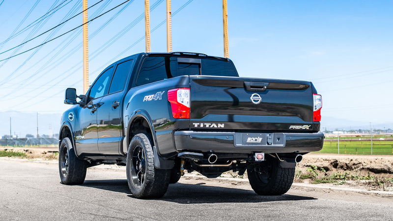 Borla S-Type Cat-Back Exhaust System installed on a Nissan Titan: A black Nissan Titan crew cab parked by power lines, rear quarter view showing exhaust tips on both sides of the rear bumper