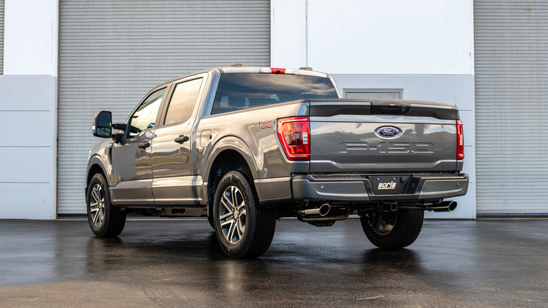 Borla S-Type Cat-Back Exhaust System installed on a Ford F-150: rear three-quarter view of a gray Ford F-150 crew cab on wet pavement in front of a roll-up door