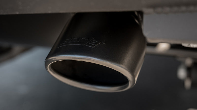 Close-up of the Borla Touring Axle-Back Exhaust System: close-up of a black exhaust tip with an etched Borla logo installed beneath a vehicle