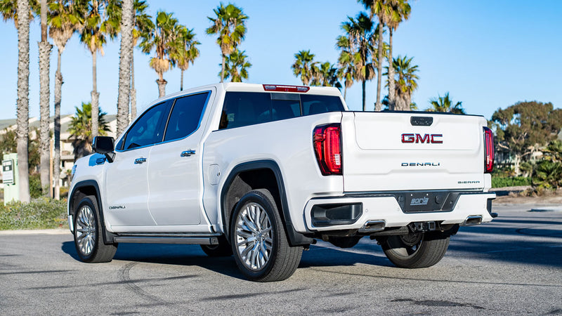 Borla Touring Cat-Back Exhaust System installed on a GMC Sierra 1500: A white GMC Sierra 1500 Denali parked under palm trees, seen from the rear quarter with a Borla plate