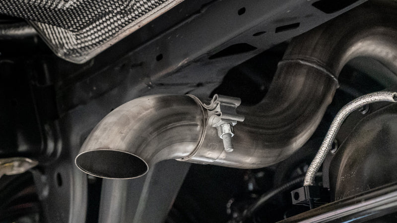 Borla Touring Cat-Back Exhaust System on a vehicle: an underbody close-up of a stainless exhaust outlet pipe secured with a band clamp near the frame