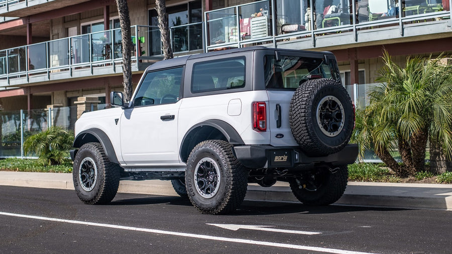 Axle-Back Exhaust Systems by Borla: A white two-door Ford Bronco with a spare tire parked on a street seen from the rear quarter.
