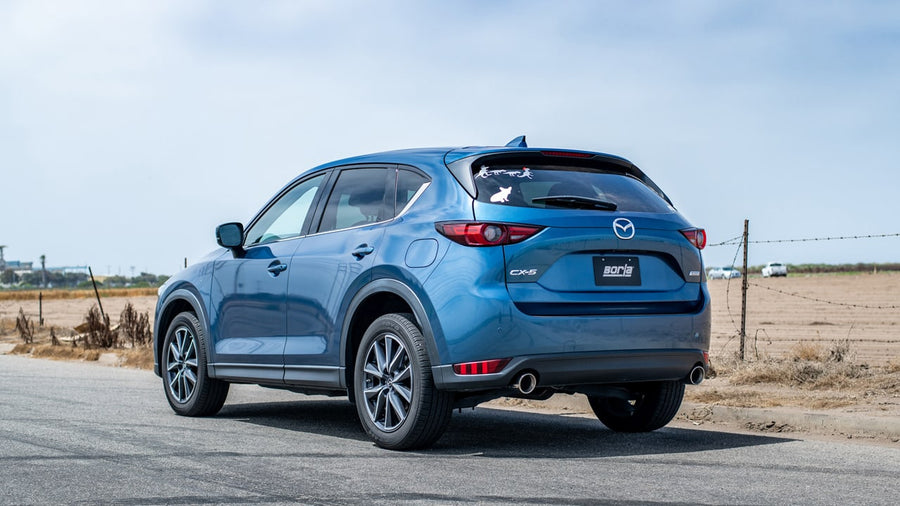 Axle-Back Exhaust Systems by Borla: A blue Mazda CX-5 parked on a rural road seen from the rear quarter.